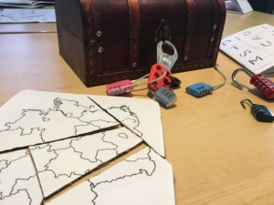 Eine Übung bei BreakoutEdu: Eine Deutschlandkarte als Puzzle liegt vor der immer noch verschlossenen Schatztruhe
